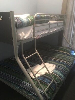 Una cama litera con estructura metálica y ropa de cama estampada.