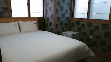 Ein Schlafzimmer mit einem Bett, zwei Kissen, einem Nachttisch und einem Wandheizkörper.