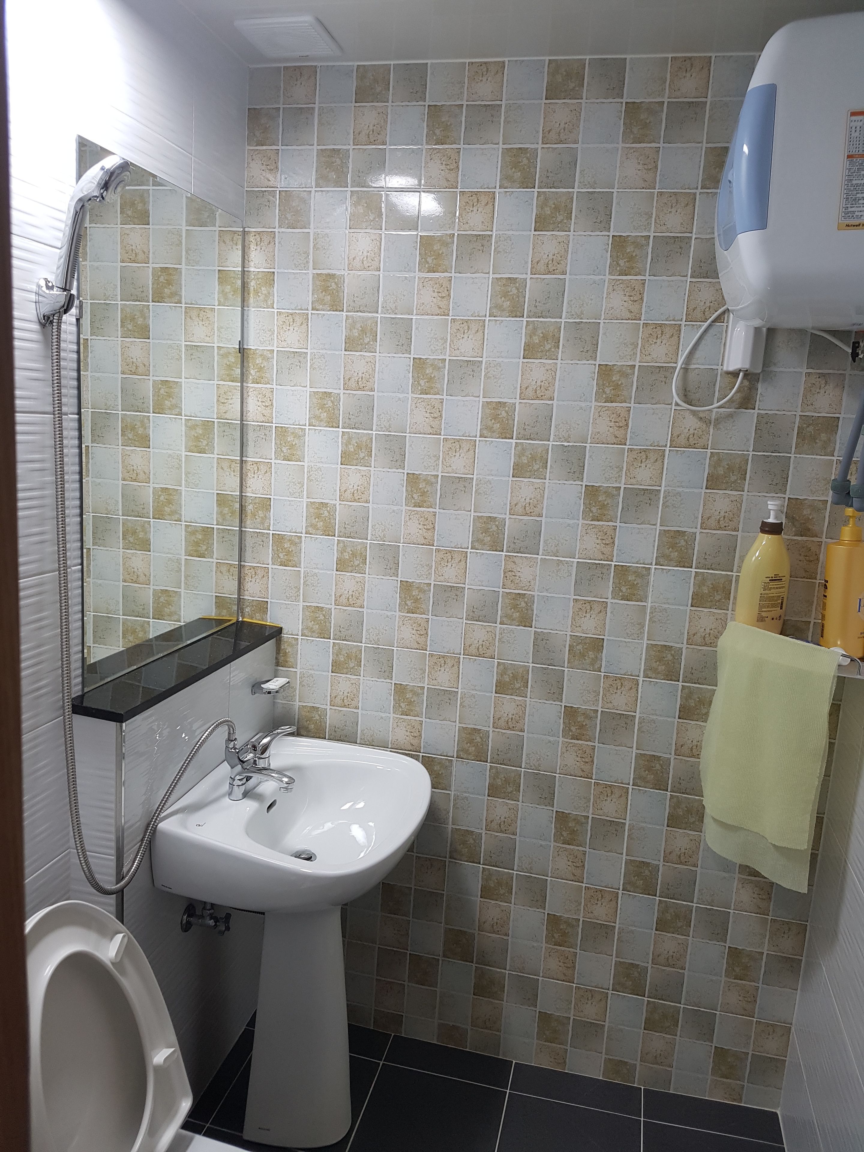 A bathroom with a white sink, a mirror, a shower, and tiled walls.