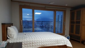A bedroom with a large window, a bed, a wooden headboard, and a nightstand. - The View Hostel (Tongyeong)