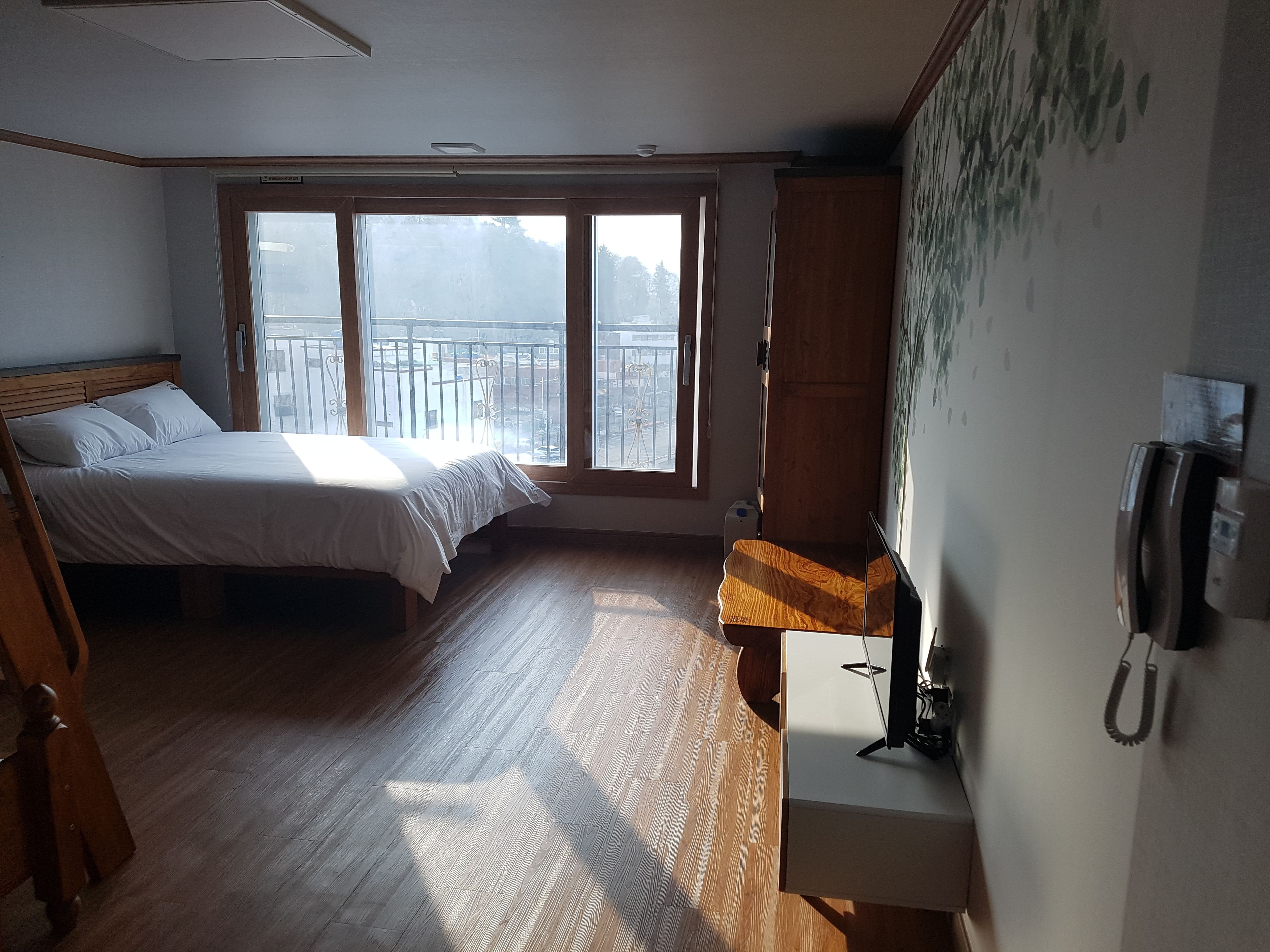 Une chambre à coucher comprenant un lit, un bureau, un téléphone et une fenêtre donnant sur l’extérieur.