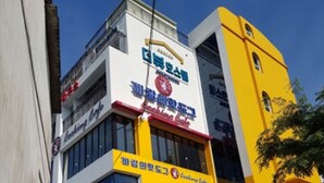 A multi-story building with a yellow facade and a sign that reads "Cooking Cafe." - The View Hostel (Tongyeong)