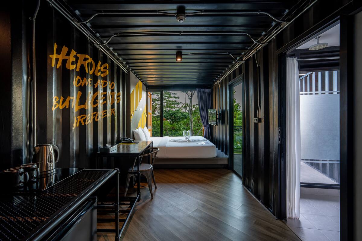Una habitación de hotel moderna con una cama, un escritorio con cafetera y vistas a zonas verdes.