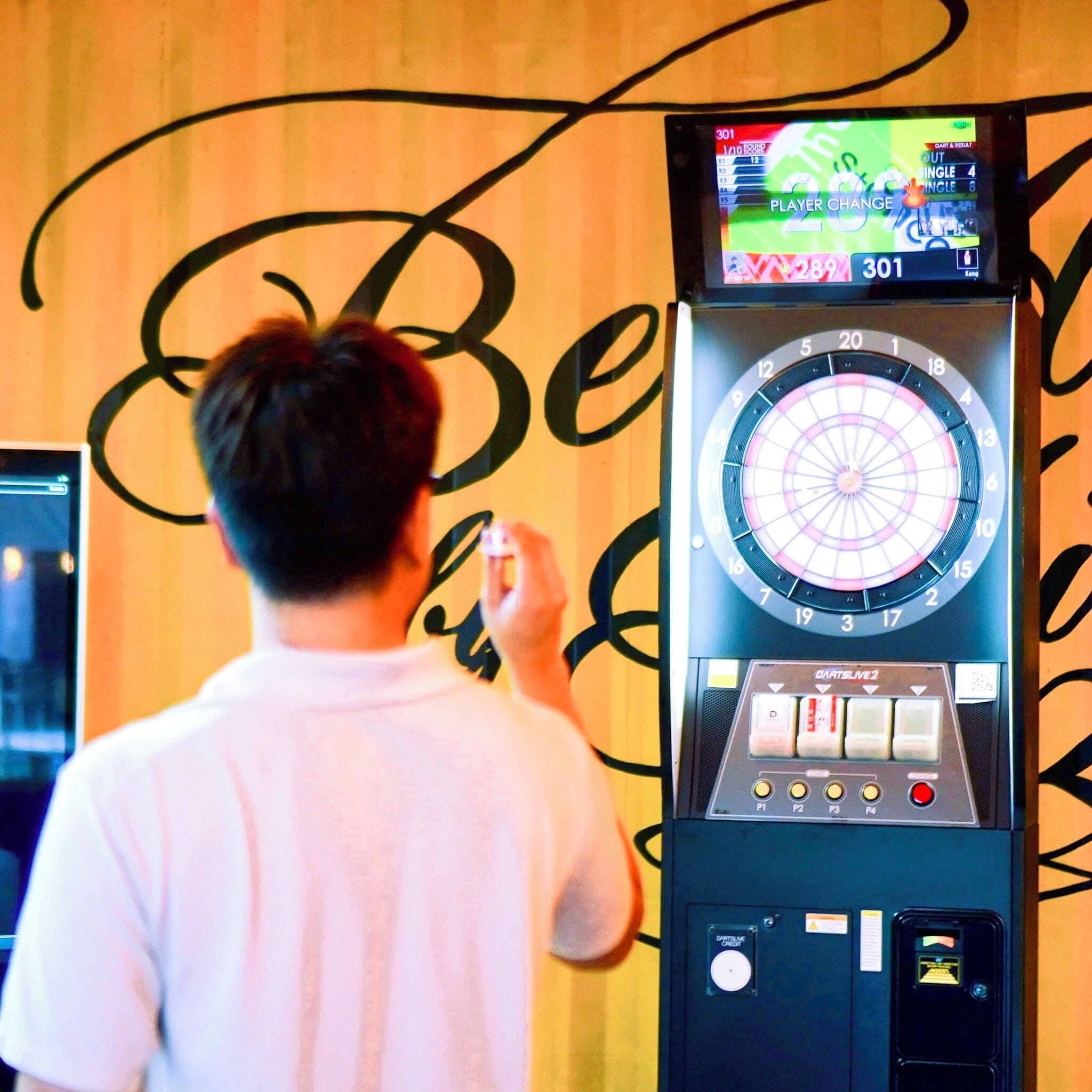 A dartboard with a digital scoreboard and a dart throwing machine.