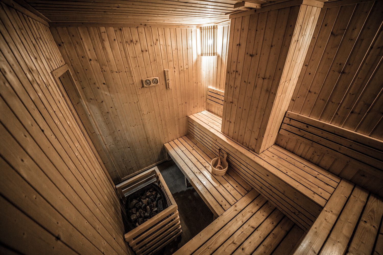 A sauna with wooden walls and benches, a small window, and a firebox with logs.