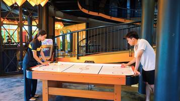 A table hockey game in a modern indoor setting with a staircase and industrial-style lighting.