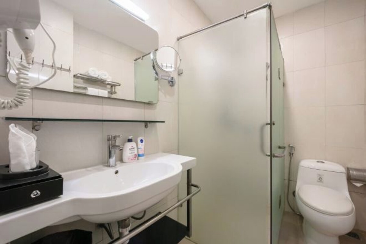 Une salle de bain moderne avec un lavabo blanc, une douche à parois de verre et des toilettes.