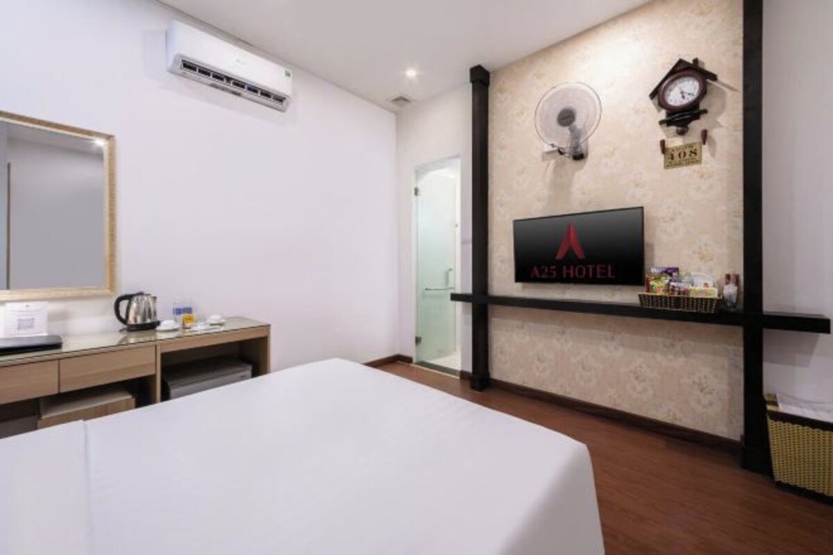 Une chambre d’hôtel avec un lit, un bureau doté d’une bouilloire, une télévision et une horloge murale.