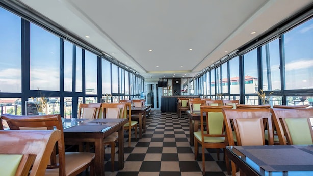 Un restaurant avec un sol à carreaux, des tables et des chaises en bois, de grandes fenêtres et une vue sur la ville.