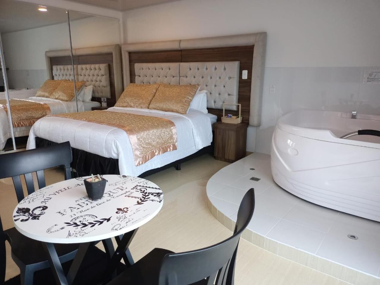 Une chambre d’hôtel avec deux lits, une table de salle à manger ronde et un jacuzzi.