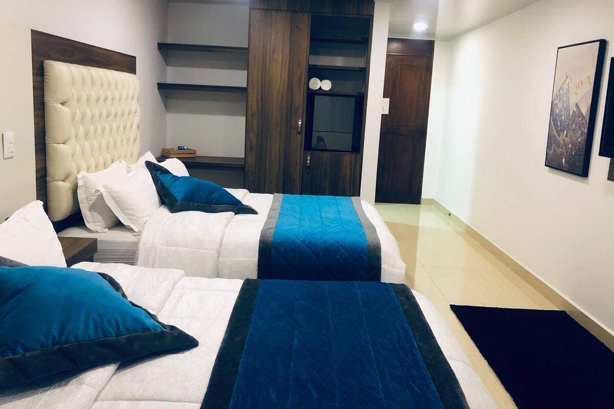 Una habitación de hotel con dos camas, un armario de madera, un escritorio y una mesita.
