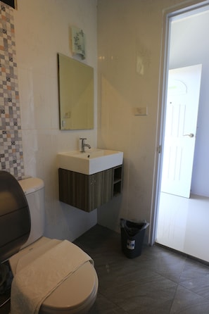 A bathroom with a toilet, sink, mirror, and a trash bin. - Mimianan Resort And Hotel (Nan)