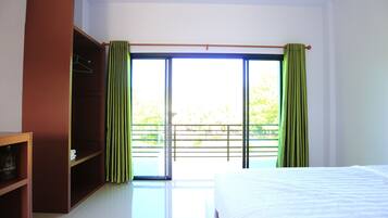 A bedroom with a bed, a wardrobe, and a balcony with curtains.