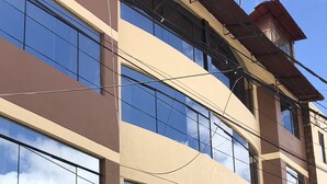 Un edificio de varios pisos con amplios ventanales, un nivel inferior con azulejos y una puerta visible.