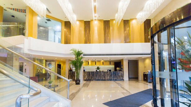 A modern hotel lobby with a reception desk, a staircase, and a glass elevator. - Shanghai Pudong Airport Yueshangju Hotel (Shanghai)