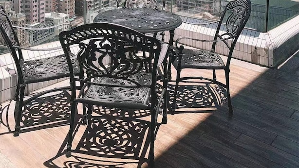 Uma varanda com mesa e cadeiras, oferecendo vista da cidade com edifícios altos e montanhas ao fundo.