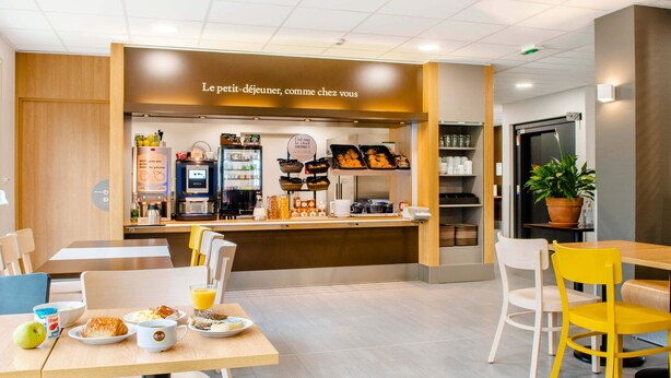 A breakfast area with a counter, seating, and a variety of food items. - B&B Hotel Nantes Savenay (Savenay)