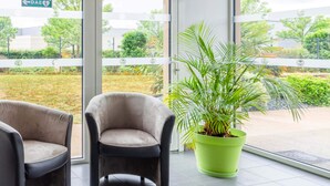 A waiting area with two chairs and a potted plant. - B&B Hotel Nantes Savenay (Savenay)