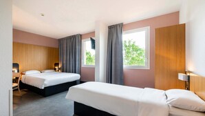 A hotel room with two beds, a desk, and a window with curtains. - B&B Hotel Nantes Savenay (Savenay)