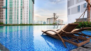 A swimming pool with blue mosaic tiles, surrounded by tall residential buildings. - Infinity Edge Pool Rivergate (Ho Chi Minh City)