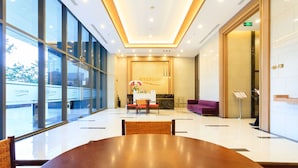 A spacious lobby with a large wooden table, a reception desk, and a purple sofa. - Infinity Edge Pool Rivergate (Ho Chi Minh City)