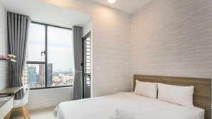 A modern hotel room with a large bed, a desk, and a view of the city through a large window. - Infinity Edge Pool Rivergate (Ho Chi Minh City)