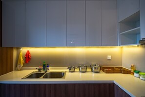 Uma cozinha moderna com uma pia dupla, panelas de aço inoxidável, um cesto e uma garrafa de detergente.