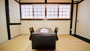 A tatami mat room with a low table and two chairs, a window with shoji screens, and a wooden floor. - Kumoi Kiyomizu (Kyoto)