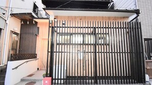 A residential building with a black metal gate, a wooden door, and a small set of steps leading to the entrance. - Kumoi Kiyomizu (Kyoto)