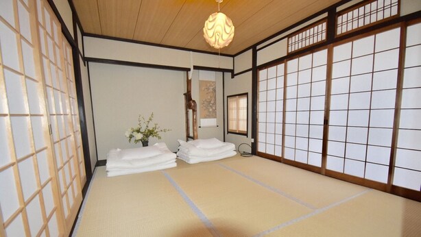 A tatami mat room with a shoji screen, a hanging light fixture, and a small vase with flowers. - Kumoi Kiyomizu (Kyoto)