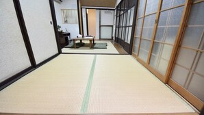A tatami mat room with a wooden floor, sliding doors, and a small table with cushions. - Kumoi Jurakumawari (Kyoto)