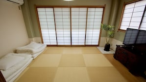 A room with tatami flooring, a futon bed, a potted plant, a TV, and a dresser. - Kumoi Tofukuji (Kyoto)