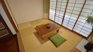 A traditional Japanese room with tatami flooring, a low wooden table with a green cushion, and a shoji screen door. - Kumoi Tofukuji (Kyoto)