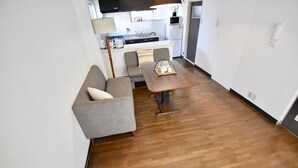 A compact living space with a kitchenette, a sofa, a dining table, and a wooden floor. - Kumoi Tofukuji (Kyoto)