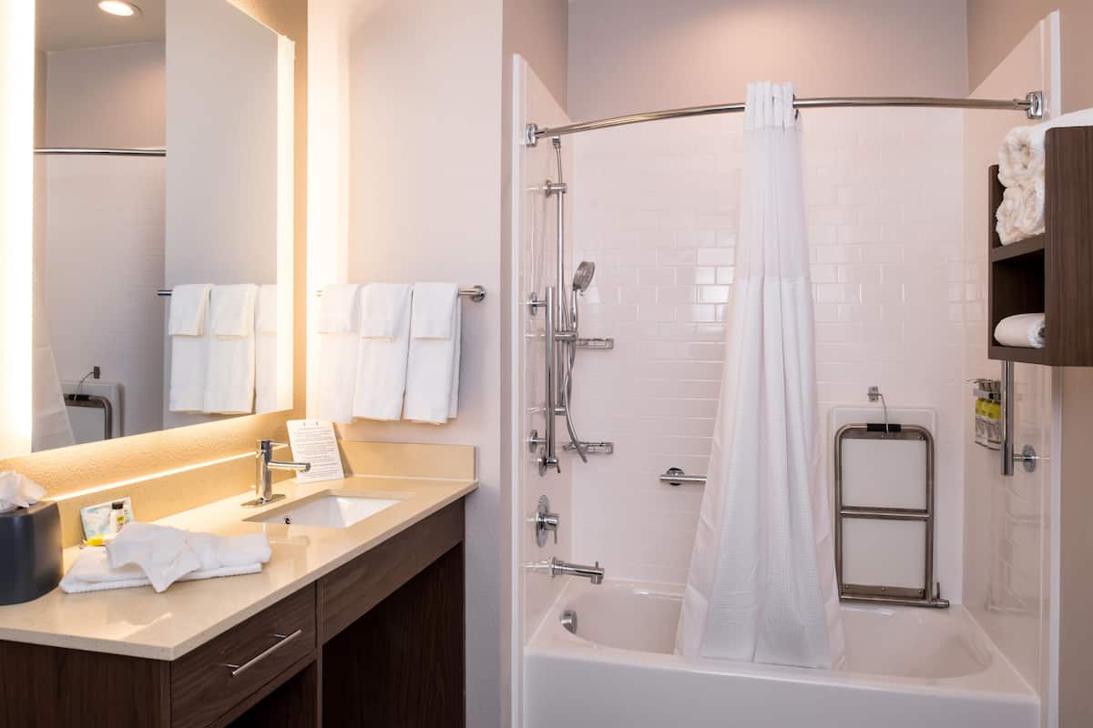 Une salle de bain moderne avec un lavabo, un miroir et un espace douche.