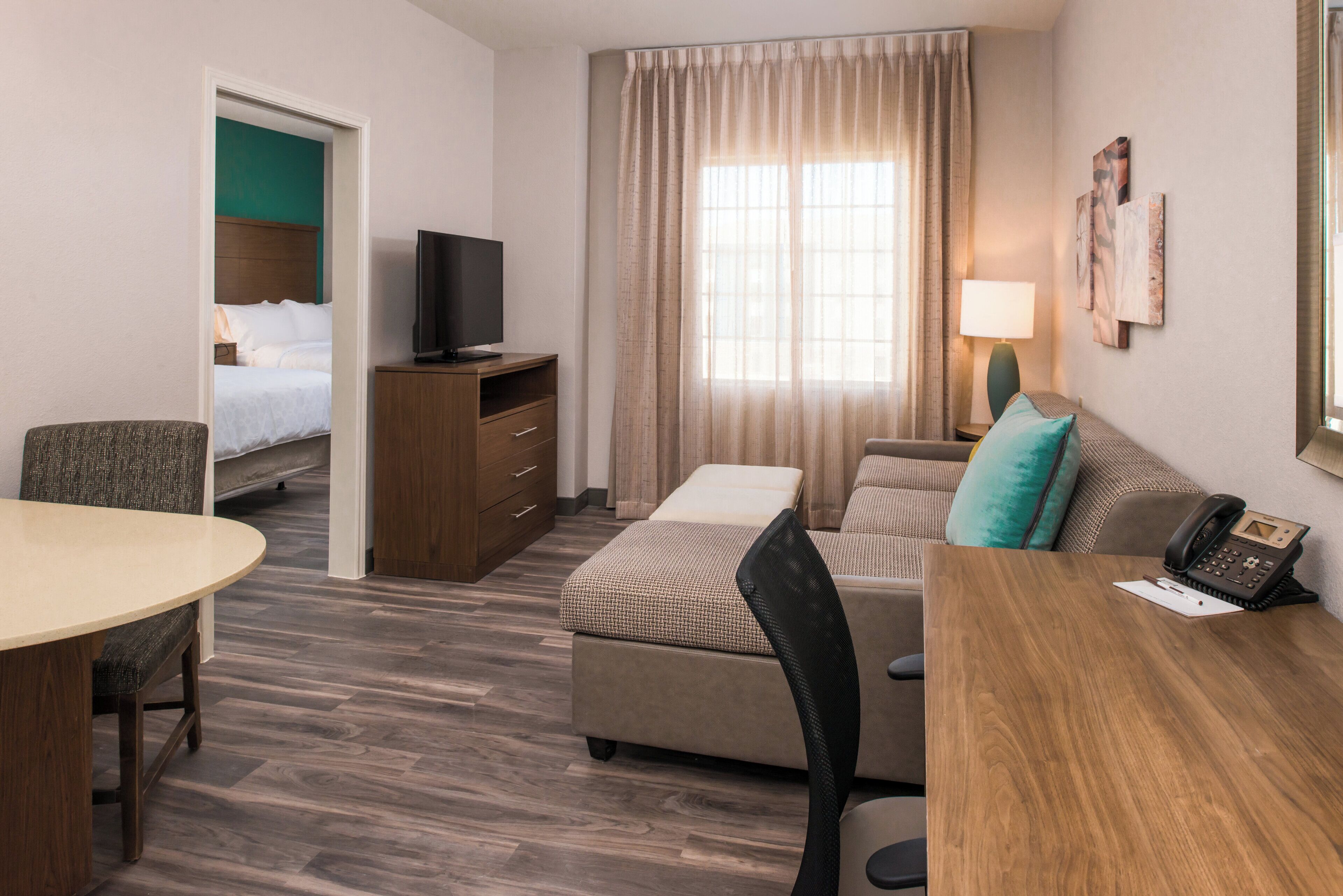 A hotel room with a bed, a desk, a chair, a television, a lamp, and a telephone.