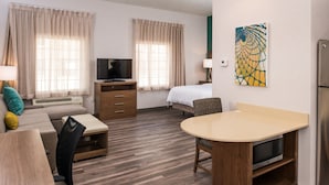 A hotel room with a bed, a TV, a desk with a microwave, a sofa, and a dining table. - Staybridge Suites Pecos by IHG (Pecos)
