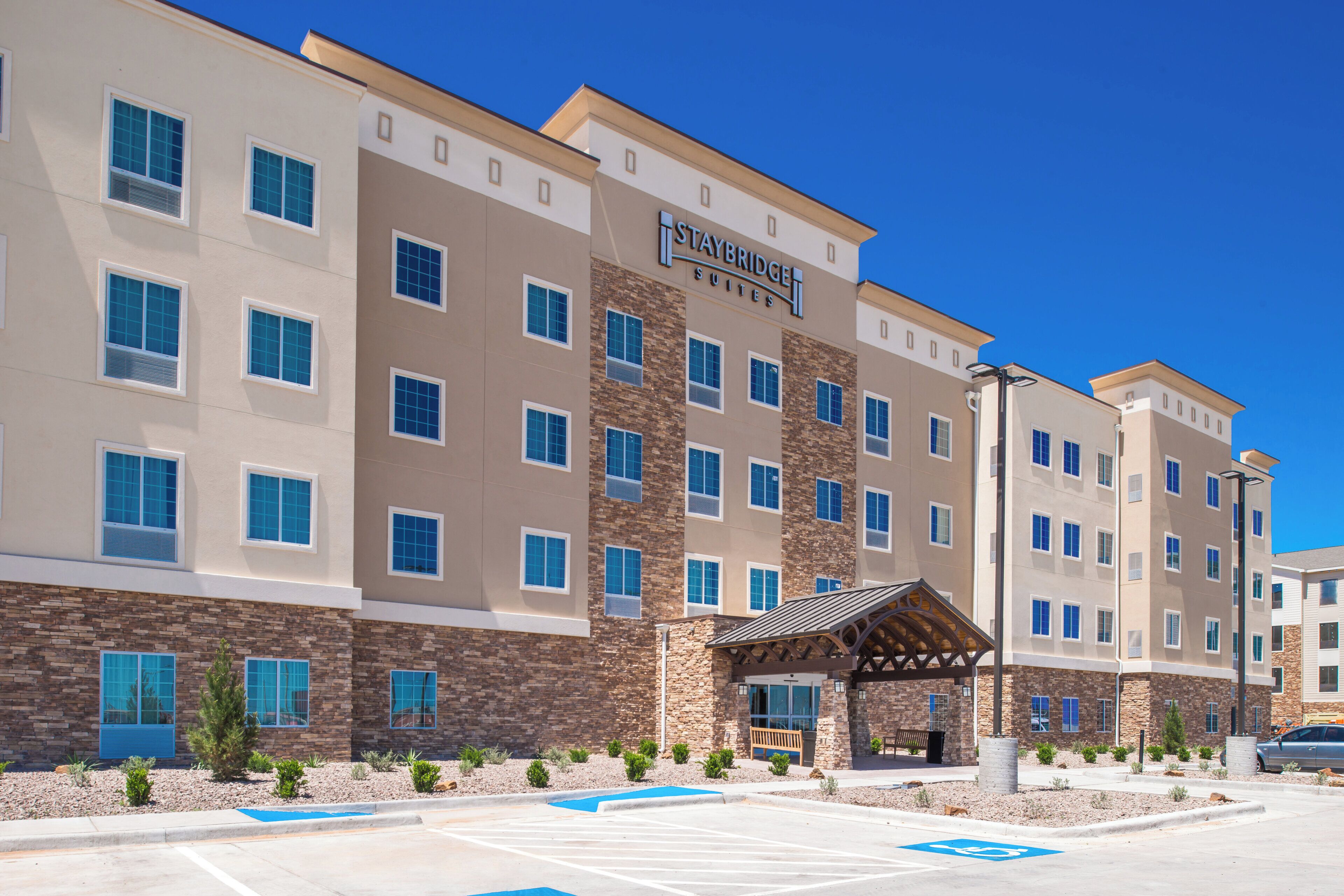 A multi-story hotel with a stone facade, Staybridge Suites branding, and a covered entrance.