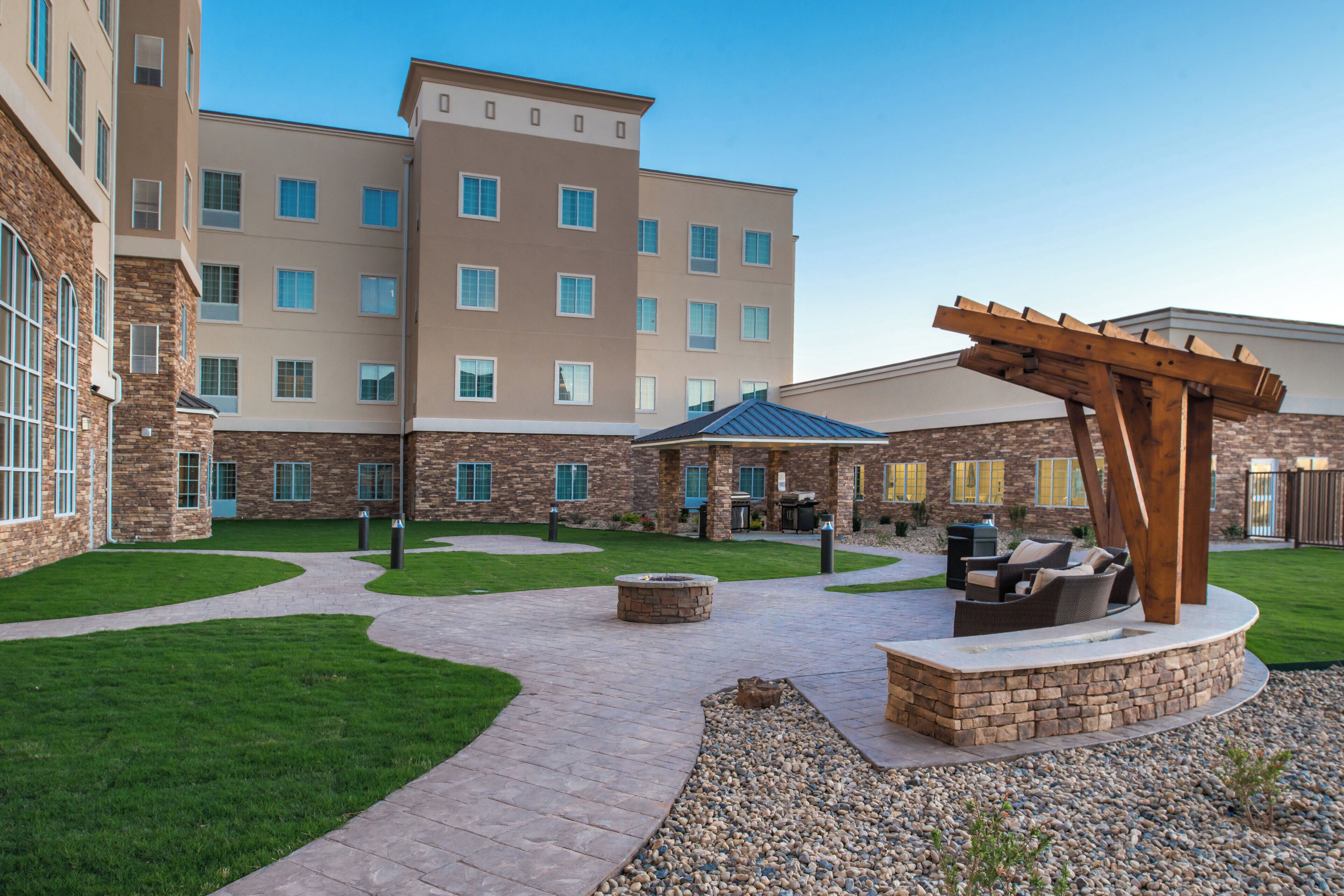 A courtyard with a pergola, outdoor seating, and a fire pit.
