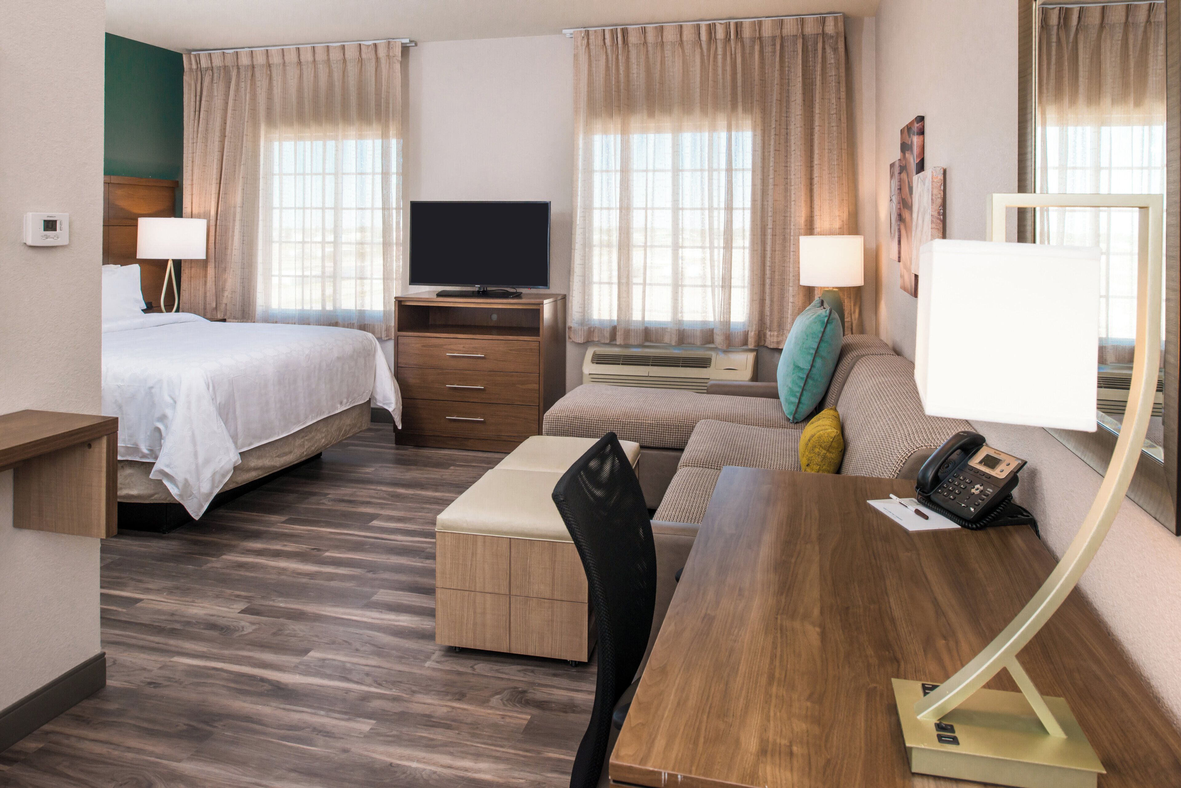 Una habitación de hotel con cama, sofá, escritorio, televisión y teléfono.