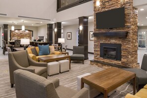 A hotel lobby with a fireplace, seating area, and a coffee station. - Staybridge Suites Pecos by IHG (Pecos)