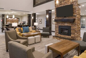 Un vestíbulo de hotel con chimenea, zona de estar y estación de café.