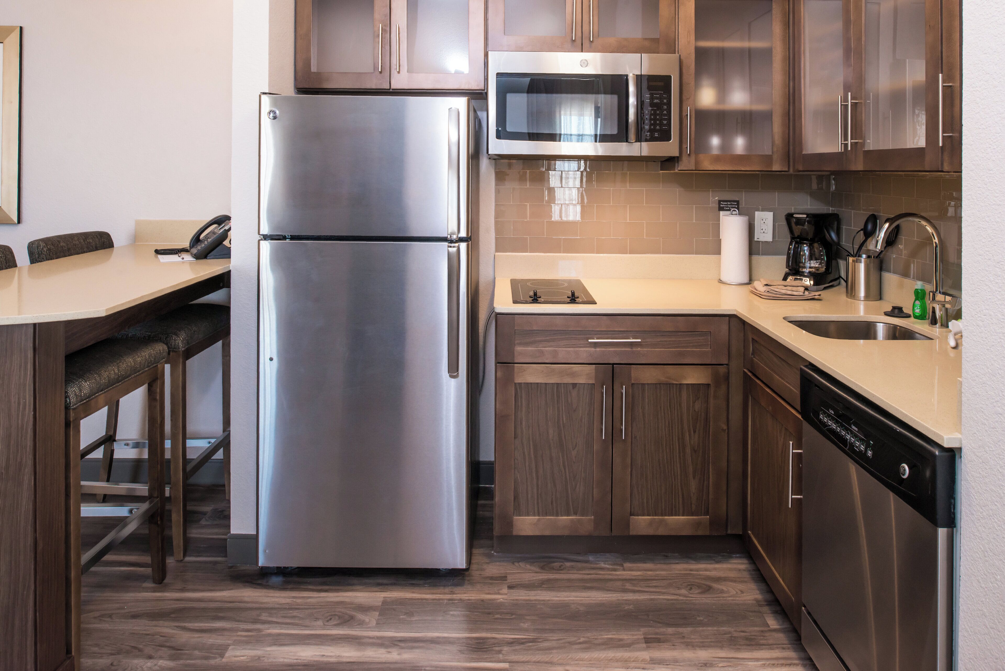 Una cocina compacta con refrigerador de acero inoxidable, microondas, horno empotrado y lavavajillas.