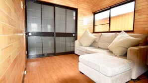Un moderno salón con suelo de madera, una puerta corrediza de vidrio y un sofá beige con cojines.