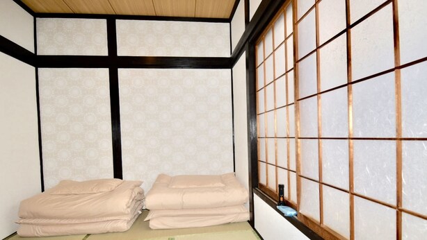 Una habitación japonesa tradicional con suelo de tatami, un biombo shoji y dos futones cuidadosamente doblados.