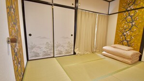 Una habitación japonesa tradicional con suelo de tatami, puertas correderas shoji y una cama futón.