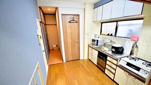 Una cocina compacta con microondas, estufa y lavabo. Una puerta de madera da a un pasillo.