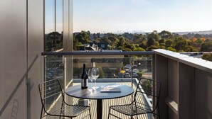 Un balcone con tavolo, sedie, una bottiglia di vino e una rivista.