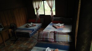 A room with two beds, a fan, and a window with curtains.