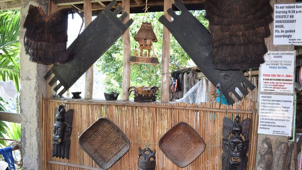 A rustic wooden structure with traditional masks and a signboard.